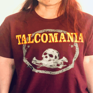 Talcomania T-Shirt Das T-Shirt ist weinrot. Es hat einen gelben Aufdruck. Die Band Talcomania macht Musik. Das T-Shirt ist gut für den Sommer.